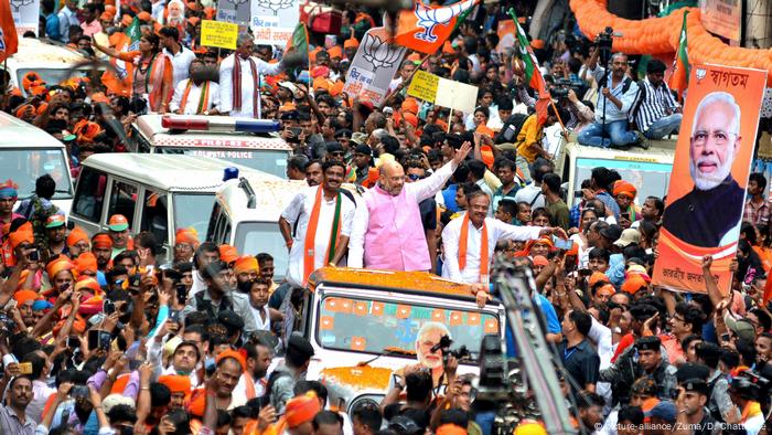 Der BJP-Parteichef Amit Shah (M.) neben einem Banner mit dem Konterfei von Premierminister Modi in Kolkata