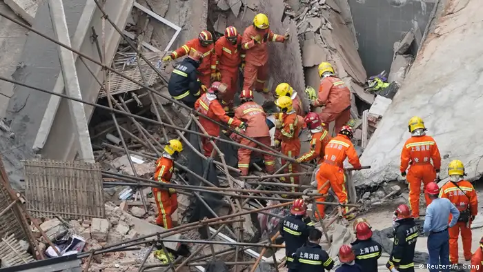 Rescue workers extract a victim from the destroyed structure in Shanghai