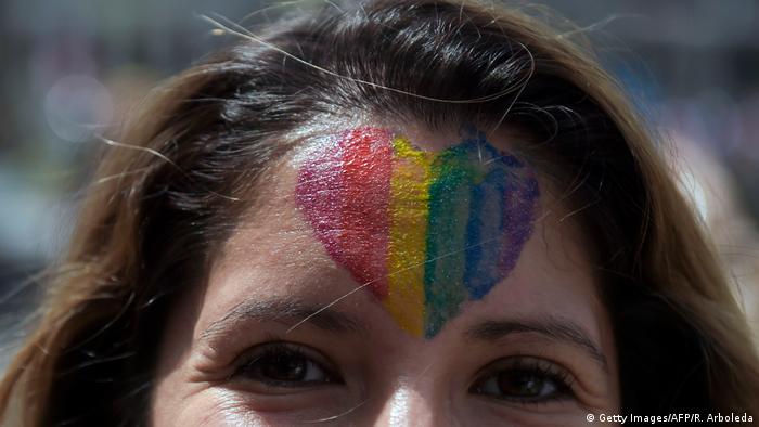 A person with a rainbow heart painted on the forehead