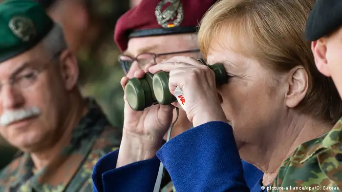 Merkel looks through binoculars at troops in Munster