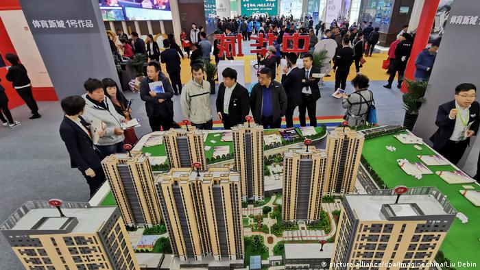 Compradores de viviendas chinos miran modelos de vivienda de un proyecto de propiedad residencial en una feria inmobiliaria en la ciudad de Dalian.