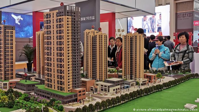 People stand next to a model of a proposed apartment block in Dalian city (picture-alliance/dpa/Imaginechina/Liu Debin)