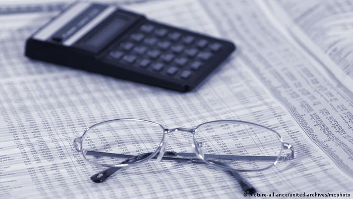 A calculator and a pair of glasses are placed on a newspaper page with market information