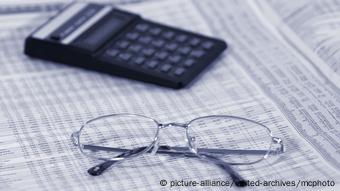 a calculator and a pair of glasses are placed on a newspaper page with market information