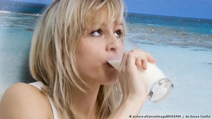 Blonde Frau in Unterwäsche trinkt ein Glas Milch