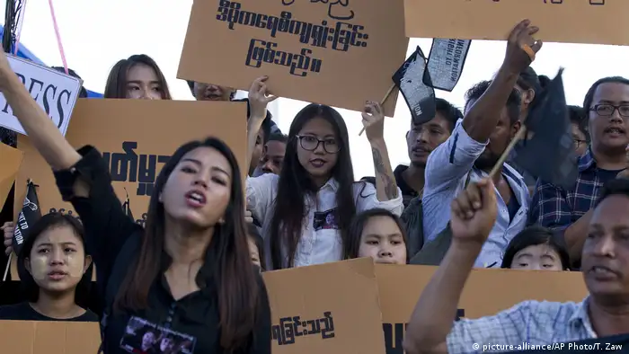 Protesters holding cardboard placards with slogans in Burmese