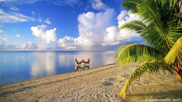 unbiased news  Two people sitting at a table in the sea on the Cook Island of Aitutaki Lagune