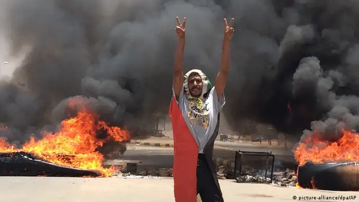 A demonstrator flashes the peace sign while debris burn in the background on June 3, 2019. (AP/dpa photo)