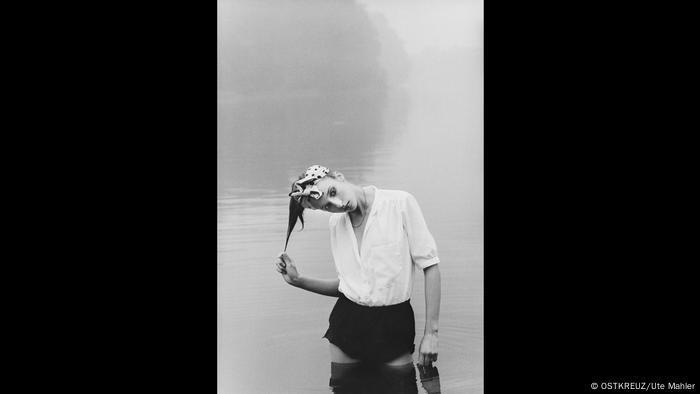 Model in heller Bluse und Hot Pants steht in einem See (OSTKREUZ/Ute Mahler)
