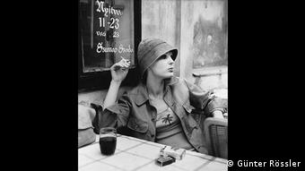 Frau sitzt rauchend vor eine Kneipe