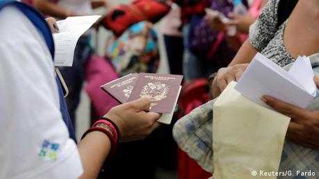 Foto simbólica de una persona de migración de Perú que sostiene dos pasaportes de Venezuela.