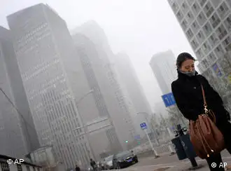 A Chinese woman walks past the Central Business District buildings shrouded by heavy fog in Beijing, China, Wednesday, Nov. 25, 2009. (AP Photo/Andy Wong)