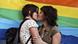 Two women kissing in front of rainbow banner Two women kissing in front of rainbow banner