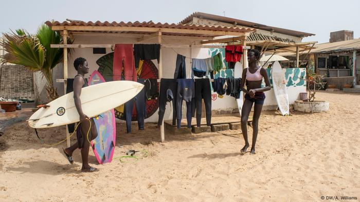 Dos mujeres africanas frente a una tienda de playa que vende artículos de surf en la costa de Senegal.