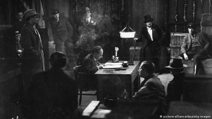 Filmszene aus Das Testament Des Dr. Mabuse mit verschiedenen Männren in einem dunklen Büro