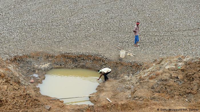 People collecting water a dried-out reservoir in Chennai, India 