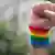A clenched fist raised with a rainbow wrist band