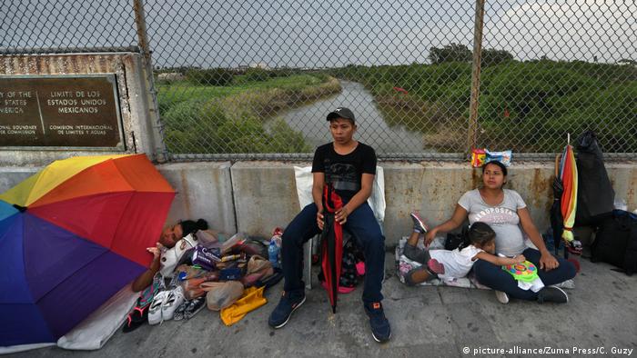 Migrants sit near the border marking at the bridge connecting Matamoros, Mexico and Brownsville, Texas.