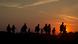 Silhouettes of refugees walking through a field Silhouettes of refugees walking through a field