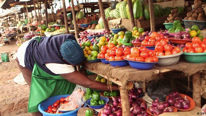 A vegetable vendor examines her products.