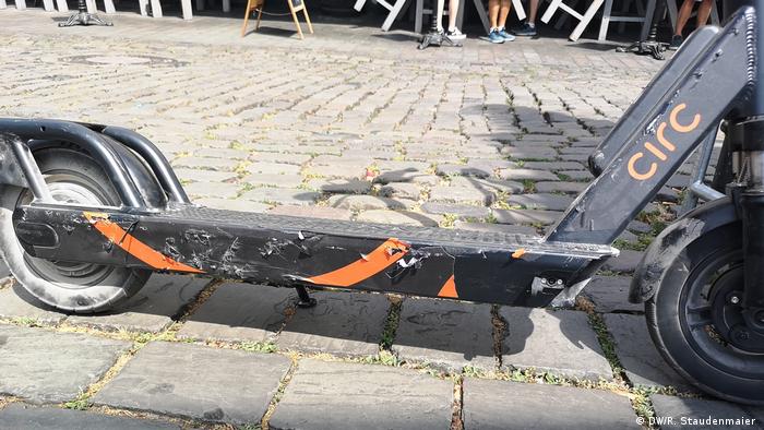 An e-Scooter with damage on its side sits on a street in Cologne, Germany