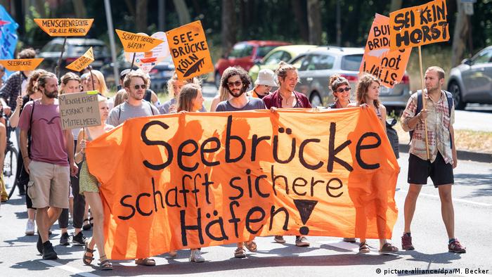 Protesters and banner reading Seebrücke makes harbors safe (picture-alliance/dpa/M. Becker)