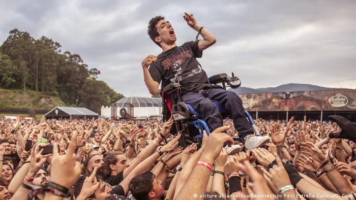 Rockfestival-Besucher in Viveiro in Spanien heben einen Rollstuhlfahrer in die Höhe