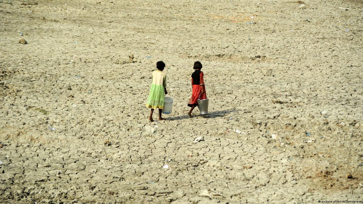 Crianças  carregando água em solo ressecado