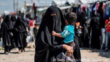 A woman displaced from Syria's eastern Deir Ezzor province, carries child as she walks in al-Hol camp for displaced people, in al-Hasakeh governorate in northeastern Syria on April 18, 2019. - Dislodged in a final offensive by a Kurdish-led ground force and coalition air strikes, thousands of wives and children of IS fighters have flooded in from a string of Syrian villages south of the al-Hol camp in recent months.
Among the hordes of Syrians and Iraqis, some 9,000 foreigners are held in a fenced section of the encampment, under the watch of Kurdish forces. (Photo by Delil SOULEIMAN / AFP) (Photo credit should read DELIL SOULEIMAN/AFP/Getty Images)