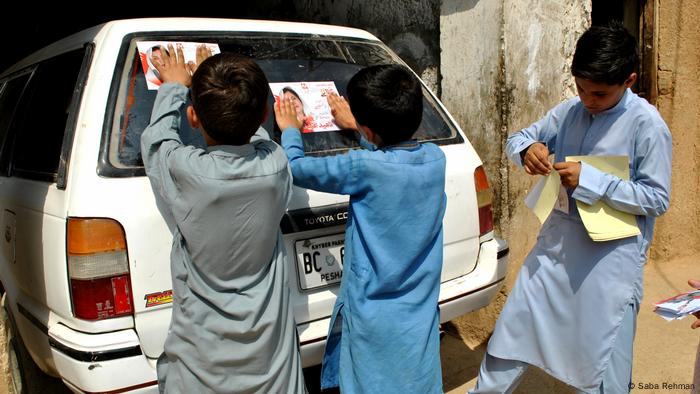 Boys paste Naheed Afridi campaign stickers on a car