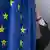A person's hand straightening an EU flag