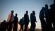 A group of migrants in a queue at dawn waiting to enter inside a police van after their arrival at the Port of Malaga A group of migrants in a queue at dawn waiting to enter inside a police van after their arrival at the Port of Malaga