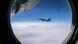 An F-16 Jet seen from the window of another airplane, flying above the clouds An F-16 Jet seen from the window of another airplane, flying above the clouds