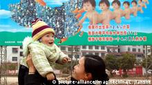 A Chinese woman lifts her child in front of a family planning propaganda advertisement in Xinshao county, central Chinas Hunan province, February 2005. Foto: Lv jianshe/Imaginechina +++(c) dpa - Report+++ |