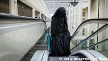 A visitor to the Second Chamber rides an escalator dressed in a niqab, prior to a debate on Islamic face covering in The Hague on November 23, 2016. - The Netherlands banned the wearing of a face-covering veil, such as a burqa or niqab, in public buildings and on transport from on August 1, 2019, as a contentious law on the garment worn by some Muslim women came into force. Between 200 and 400 women are estimated to wear a burqa or niqab in the country of 17 million people. (Photo by Bart Maat / ANP / AFP) / Netherlands OUT (Photo credit should read BART MAAT/AFP/Getty Images)