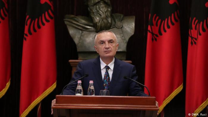 Albanian President Ilir Meta gives a speech flanked by flags
