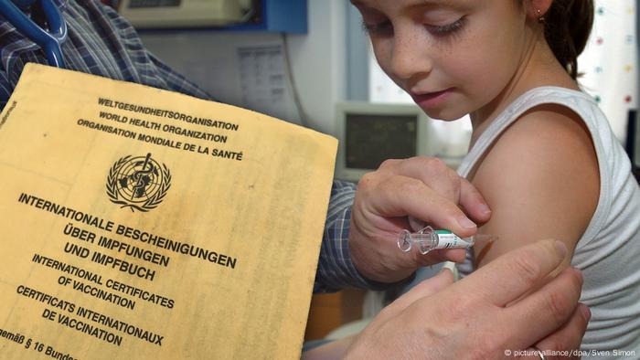 a certificate of vaccination and a child receiving injection into its arm