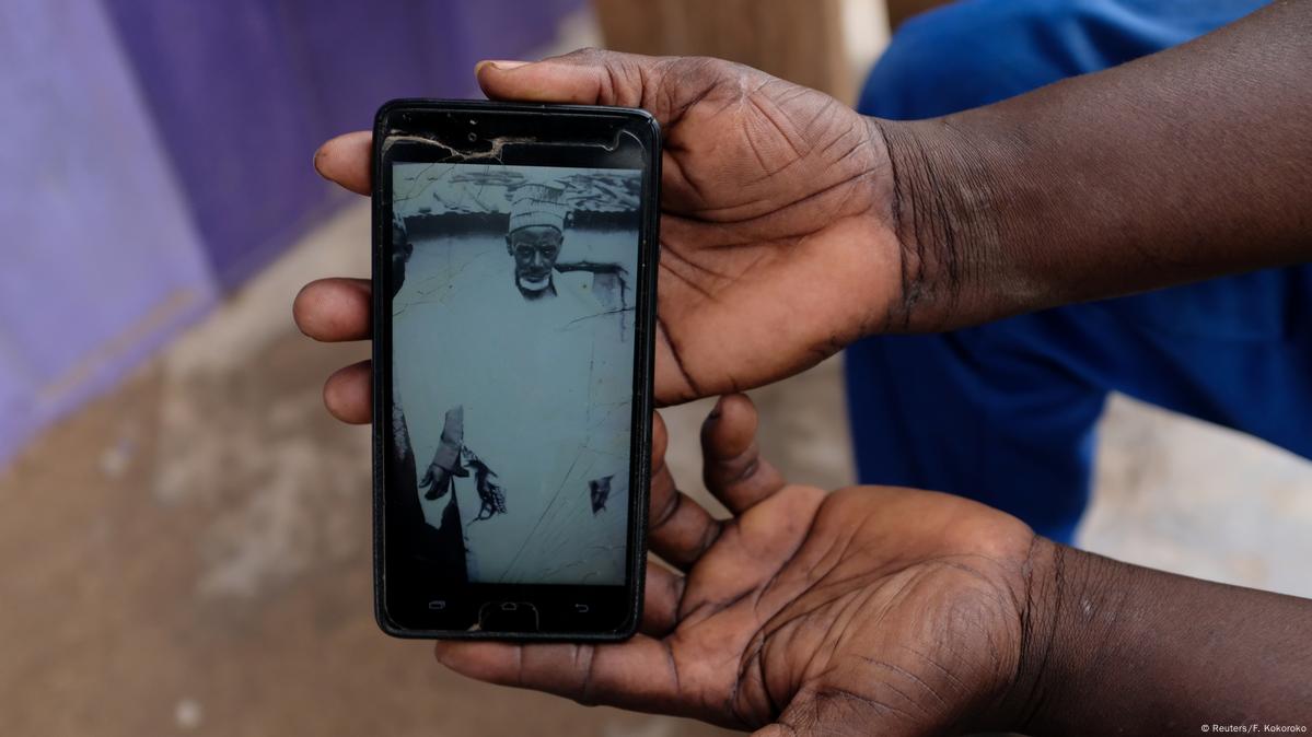 Duas mãos seguram celular com foto de idoso