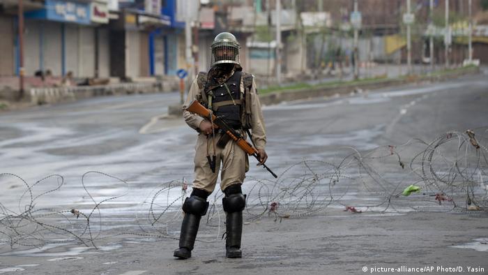An Indian Paramilitary soldier stands guard on a deserted road during curfew in Srinagar