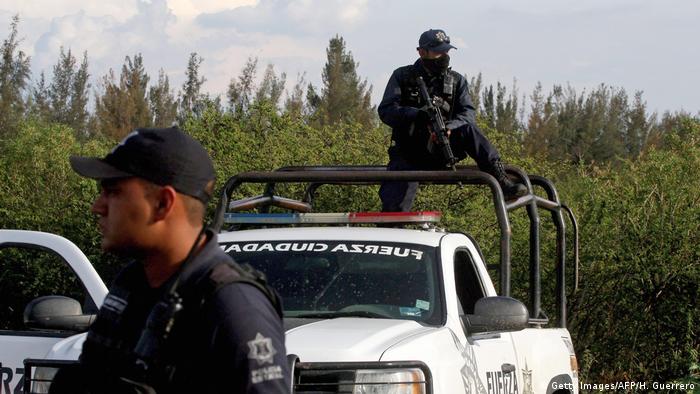 A policeman holding a gun stands on a police truck