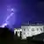 A bolt of lightening illuminates the sky behind the white house