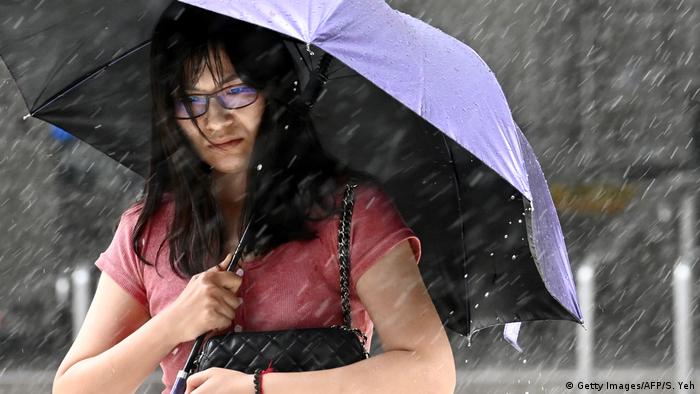 Foto simbólica de una persona con una sombrilla bajo la lluvia.