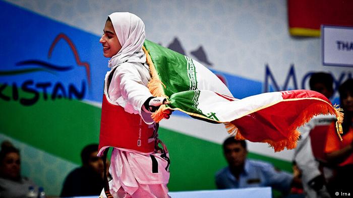A member of the Iranian girls taekwondo team carrying a national flag
