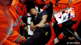Medics attempt to remove an injured man who anti-government protesters said was a Chinese policeman during a mass demonstration at the Hong Kong international airport, in Hong Kong