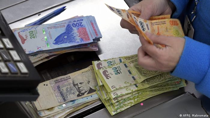 A cashier counts Argentine peso bills