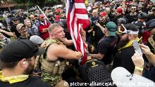 Joseph Oakman and fellow Proud Boys plant a flag in Tom McCall Waterfront Park during an End Domestic Terrorism rally in Portland, Ore., on Saturday, Aug. 17, 2019. Portland Mayor Ted Wheeler said the situation was potentially dangerous and volatile but as of early afternoon most of the right-wing groups had left the area via a downtown bridge and police used officers on bikes and in riot gear to keep black clad, helmet and mask-wearing anti-fascist protesters — known as antifa — from following them. (AP Photo/Noah Berger) |