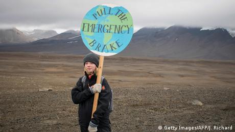 A girl attending the ceremony to mark the passing of Iceland's Okjokull ice sheet holds a globe-shaped placard with a picture of the earth and the slogan pull the emergency brake. 