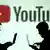 Foto simbólica de dos personas con laptops frente al logo de YouTube