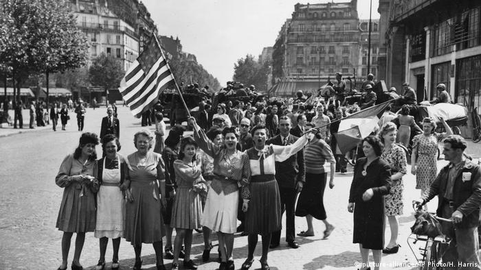 A photo of a group of women on the street waving an American flag in Paris. (Foto: picture-alliance/AP Photo/H. Harris).