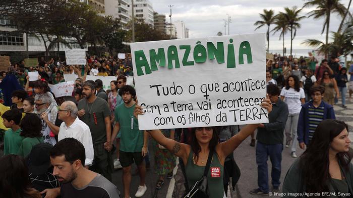 Mulher levanta cartaz durante manifestação pela Amazônia